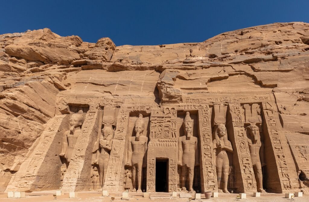 Fachada del templo menor de Nefertari en Abu Simbel tallada en el acantilado de roca bajo un cielo azul intenso, Egipto