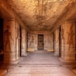 The interior hypostyle hall of the Great Temple at Abu Simbel, Osiride pillars down both sides and painted reliefs leading to the lit sanctuary at the far end