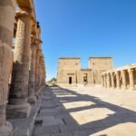 Columnata del Templo de File en Asuan Egipto, con columnas talladas con jeroglificos y el primer pilono al fondo bajo un cielo azul intenso