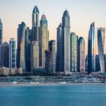 Horizonte de Dubai Marina al atardecer con rascacielos modernos reflejados en el agua azul, vista premium del skyline de lujo en Dubai