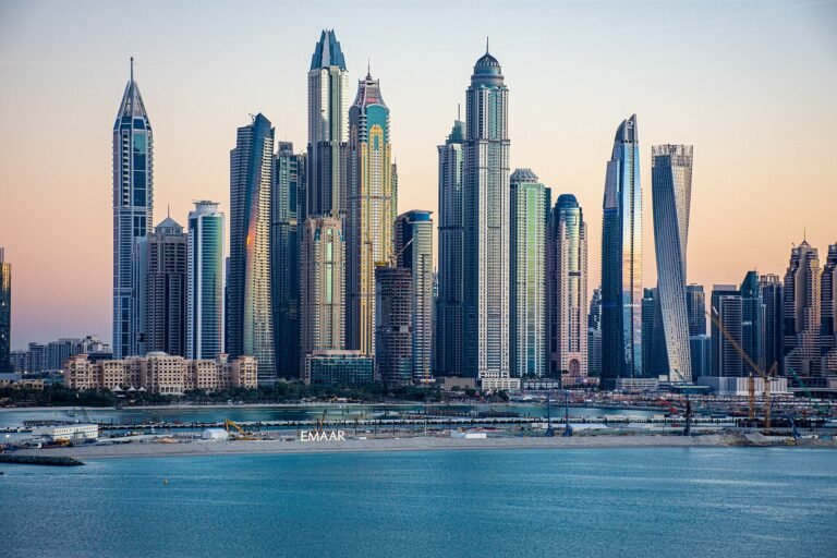 Horizonte de Dubai Marina al atardecer con rascacielos modernos reflejados en el agua azul, vista premium del skyline de lujo en Dubai