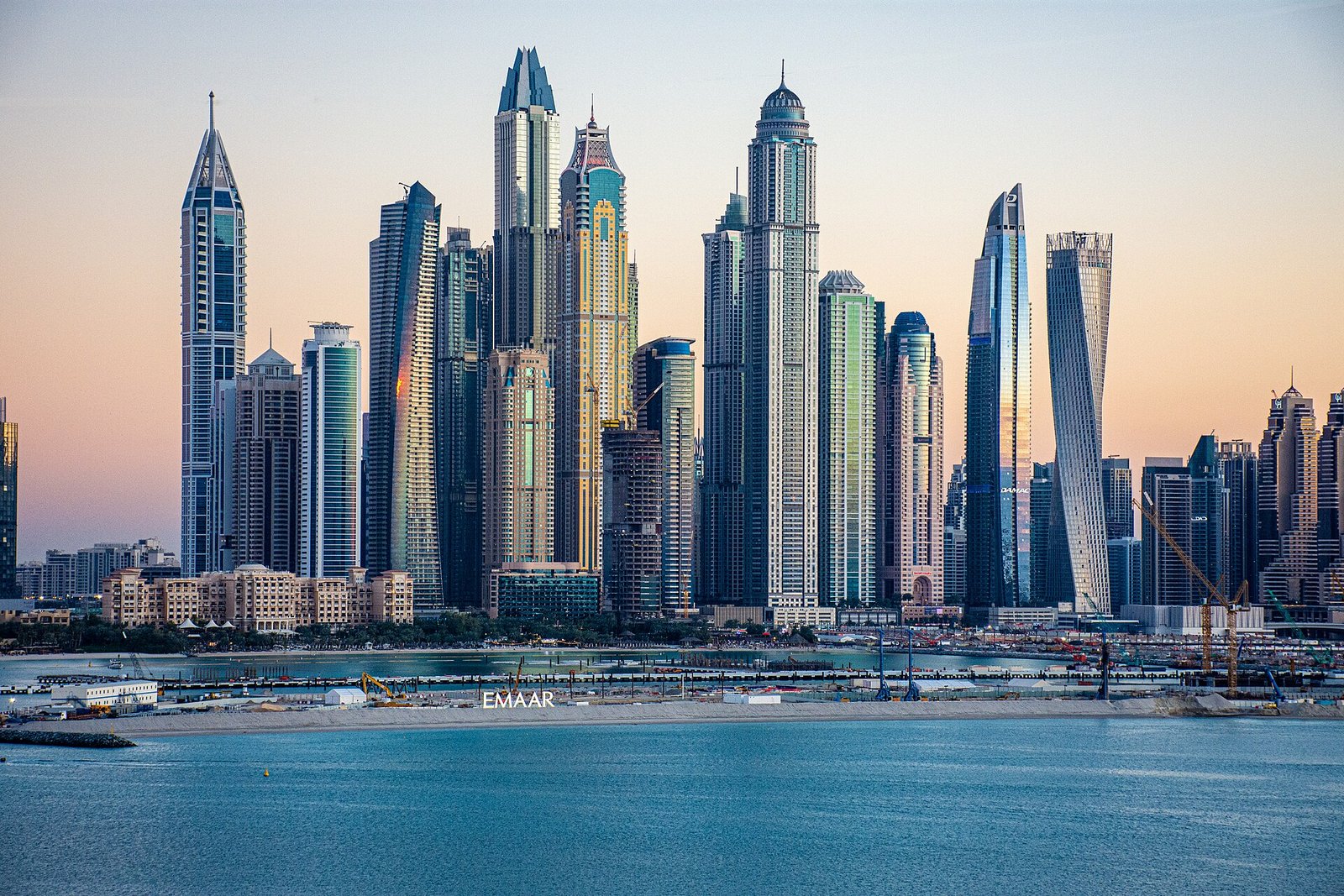 Horizonte de Dubai Marina al atardecer con rascacielos modernos reflejados en el agua azul, vista premium del skyline de lujo en Dubai