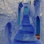 Calleja escalonada pintada de azul intenso en Chefchaouen la ciudad azul de Marruecos con peldanos y puertas azules subiendo entre muros encalados