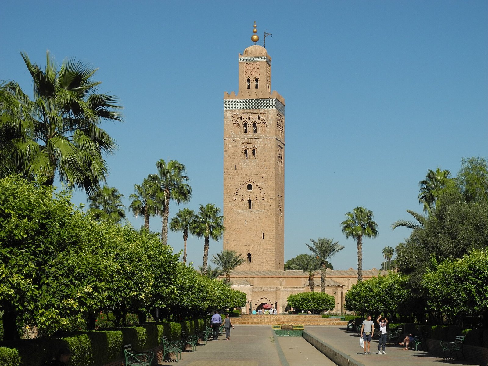 Minarete de la mezquita Koutoubia en Marrakech enmarcado por palmeras y jardines bajo un cielo azul despejado un emblema de Marruecos