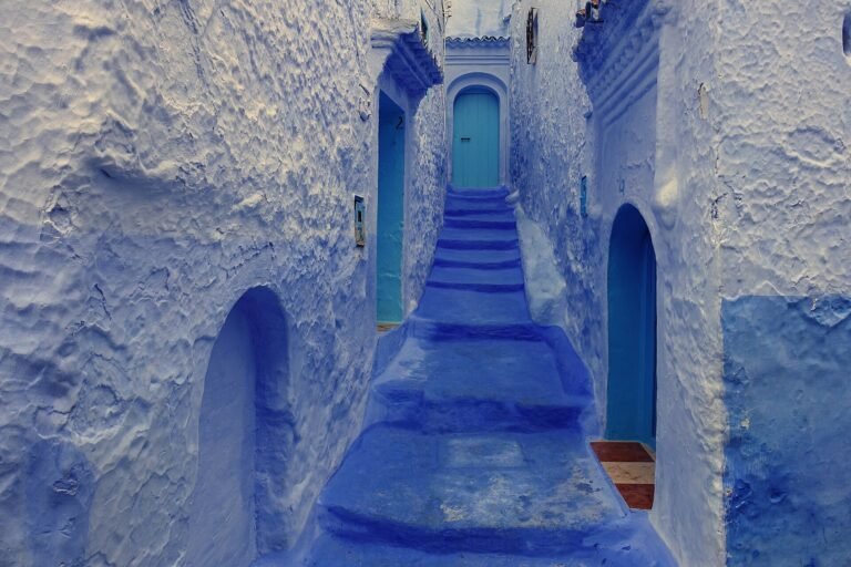 Calleja escalonada pintada de azul intenso en Chefchaouen la ciudad azul de Marruecos con peldanos y puertas azules subiendo entre muros encalados