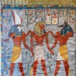 Muro pintado de una tumba del Valle de los Reyes en Luxor con Horus de cabeza de halcon, el faraon y Anubis de cabeza de chacal en rojo, azul y oro vivos