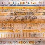 Techo de tumba faraonica en el Valle de los Reyes en Luxor Egipto con filas de figuras doradas y barcas solares pintadas sobre fondo crema y jeroglificos vivos