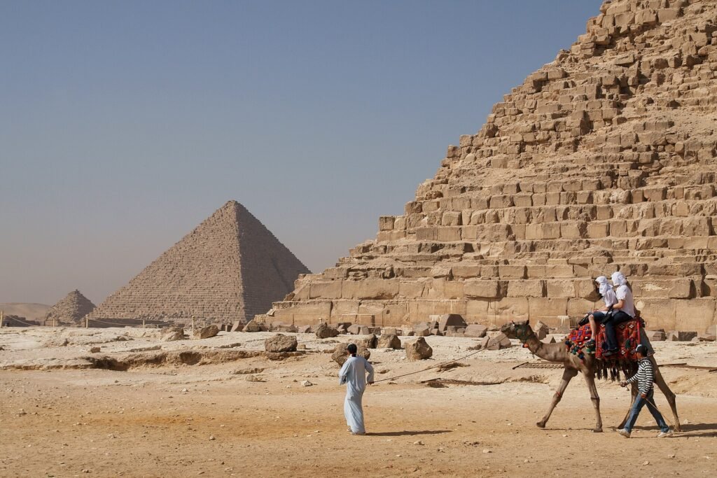 Familia viajando a Egipto con ninos montando en camello frente a las piramides de Giza