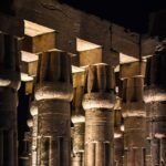 Columnas papiriformes del templo de Luxor iluminadas de noche con luz calida dorada contra el cielo negro, escena premium y limpia del patrimonio de Egipto