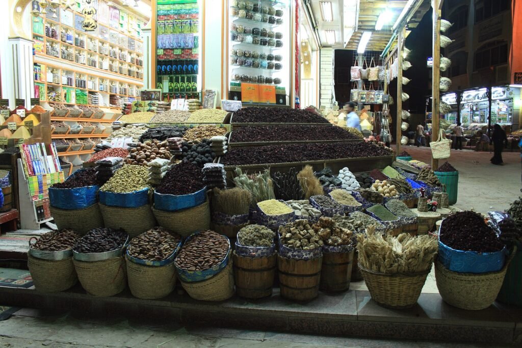 Puesto de mercado en Egipto con cestas rebosantes de datiles, hibisco, frutos secos y hierbas secas bajo luz calida, escena autentica de un zoco egipcio
