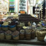 Puesto de mercado en Egipto con cestas rebosantes de datiles, hibisco, frutos secos y hierbas secas bajo luz calida, escena autentica de un zoco egipcio
