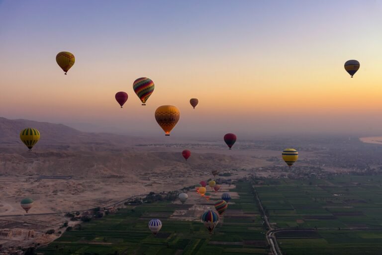 Decenas de globos aerostaticos coloridos sobrevolando el valle del Nilo y las colinas de Luxor al amanecer en Egipto, experiencia de lujo