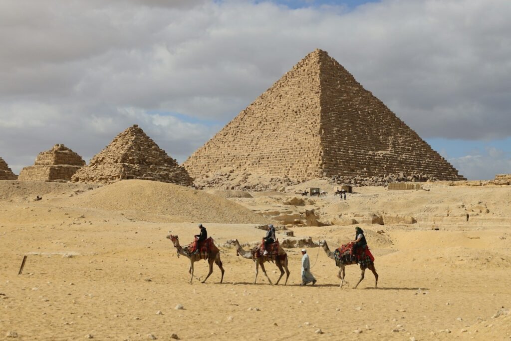 Una caravana de camellos cruza la arena ante la pirámide de Micerinos y las pirámides de las reinas en Giza