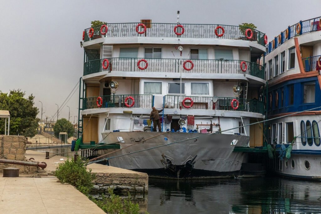 Two Nile cruise ships moored side by side, their railed decks hung with life rings