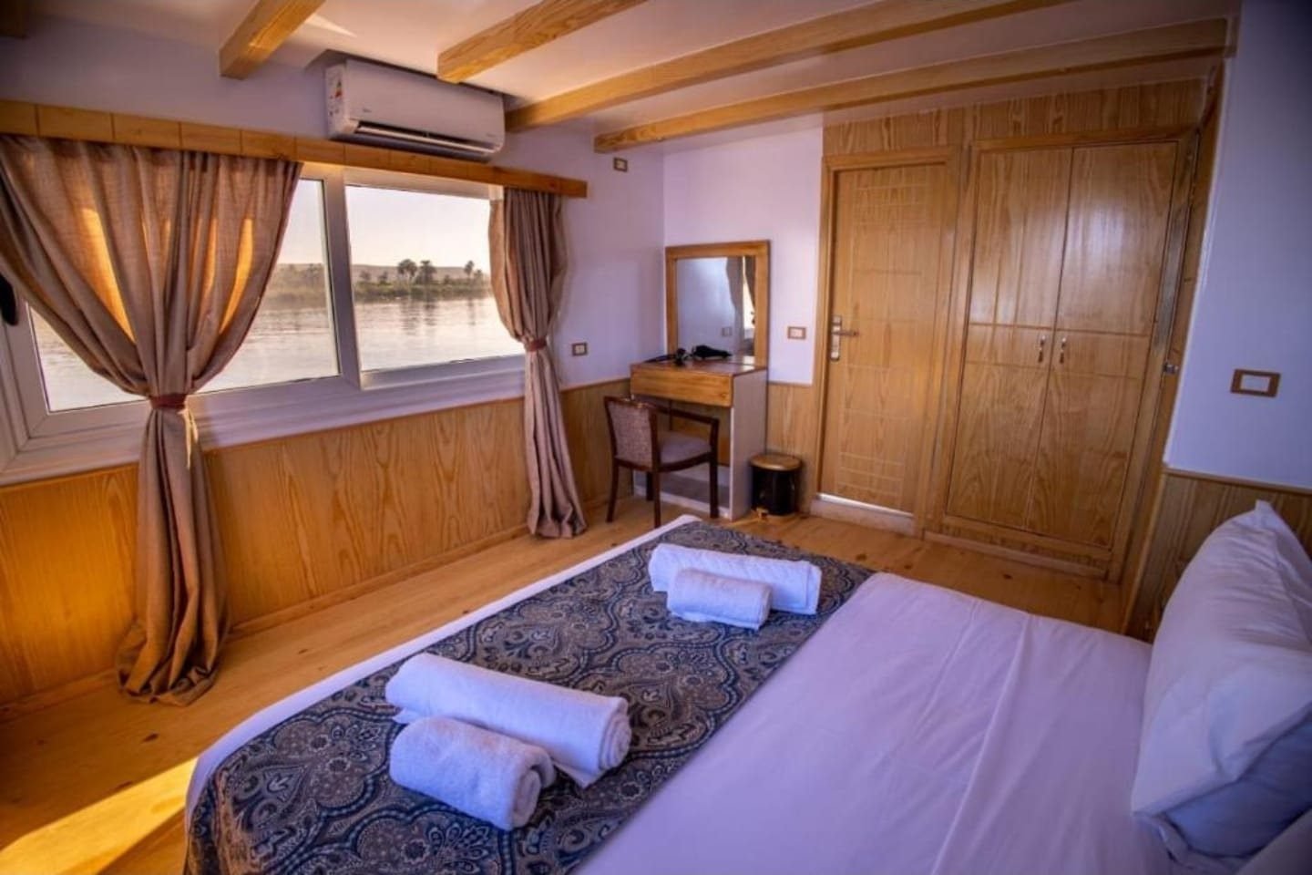 Cabina de la Akhenaton con cama doble, armario de madera y ventana al Nilo