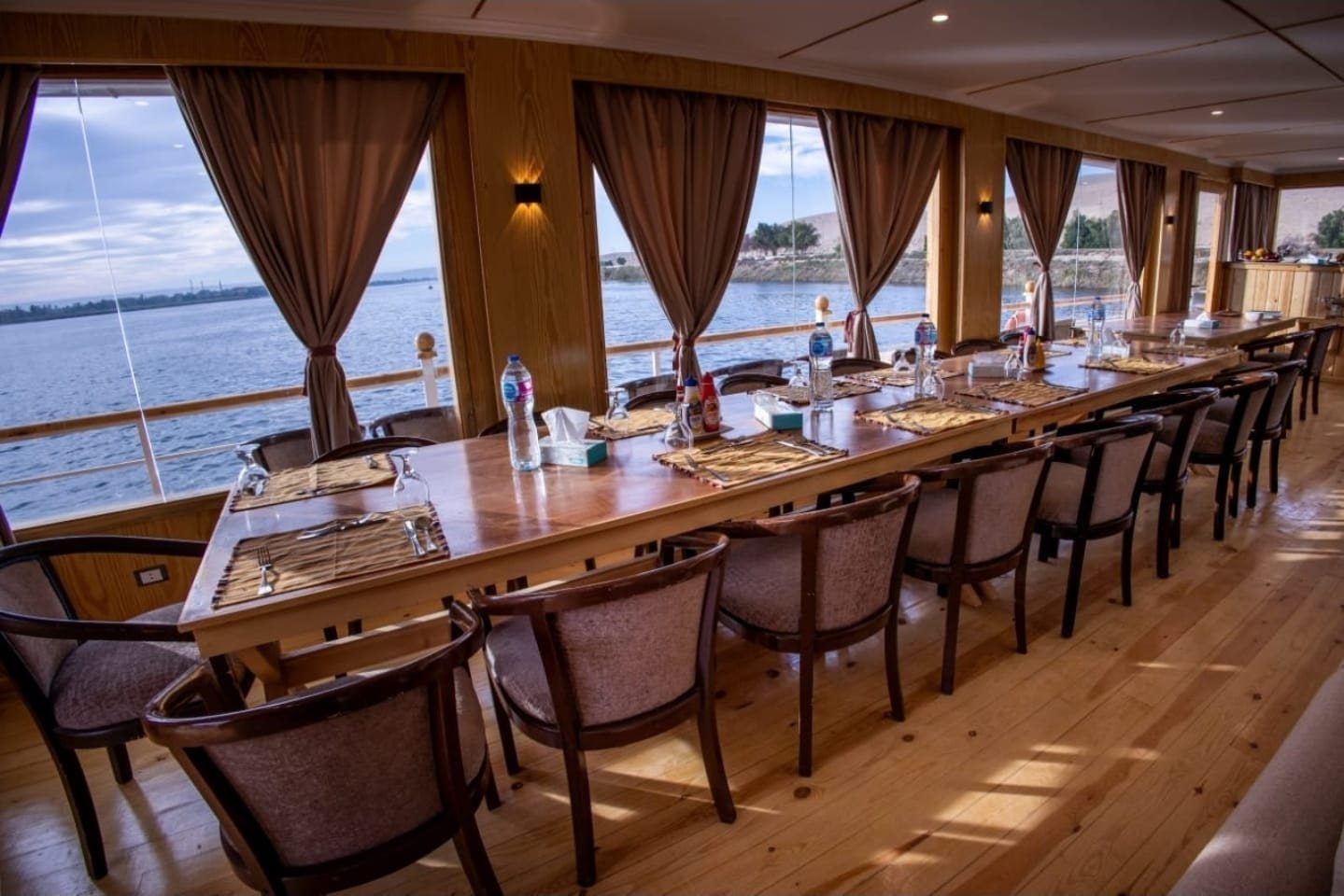 Comedor de la Akhenaton con una mesa larga y ventanales con vista al Nilo