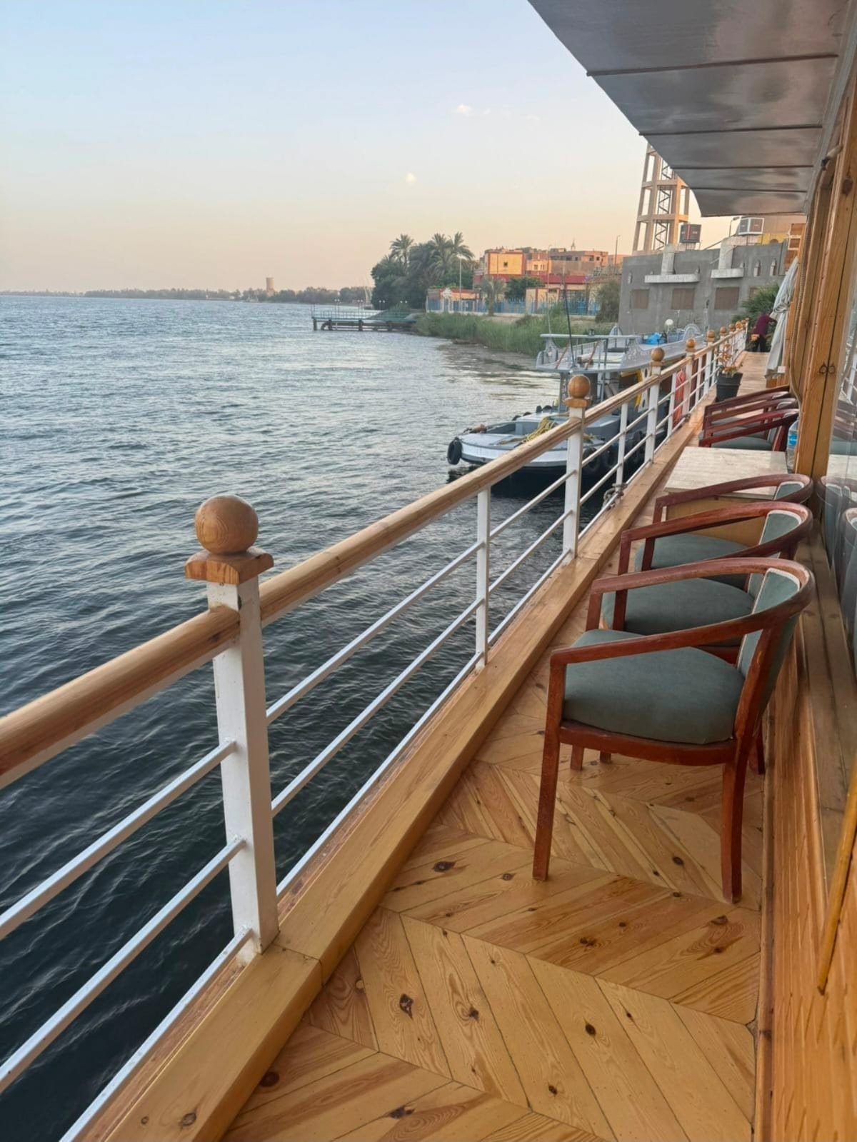 Deck promenade on the Akhenaton with chairs along the rail and the riverbank close by