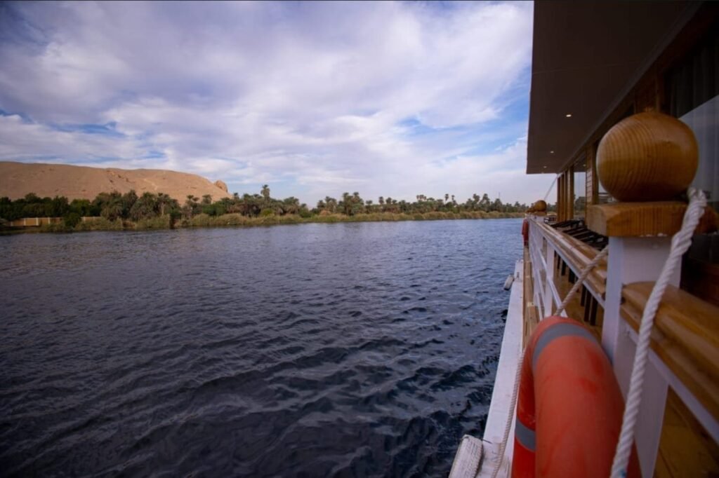 The Nile and a golden dune seen from the rail of the Akhenaton