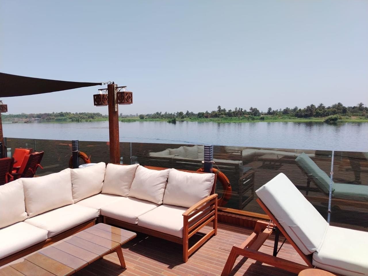 White outdoor sofa and lounger on the Iris deck, with the Nile bank behind