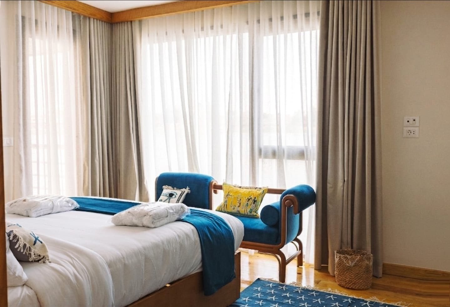 Cabina junior de la Per-ba con cama, diván azul y grandes ventanales con cortinas