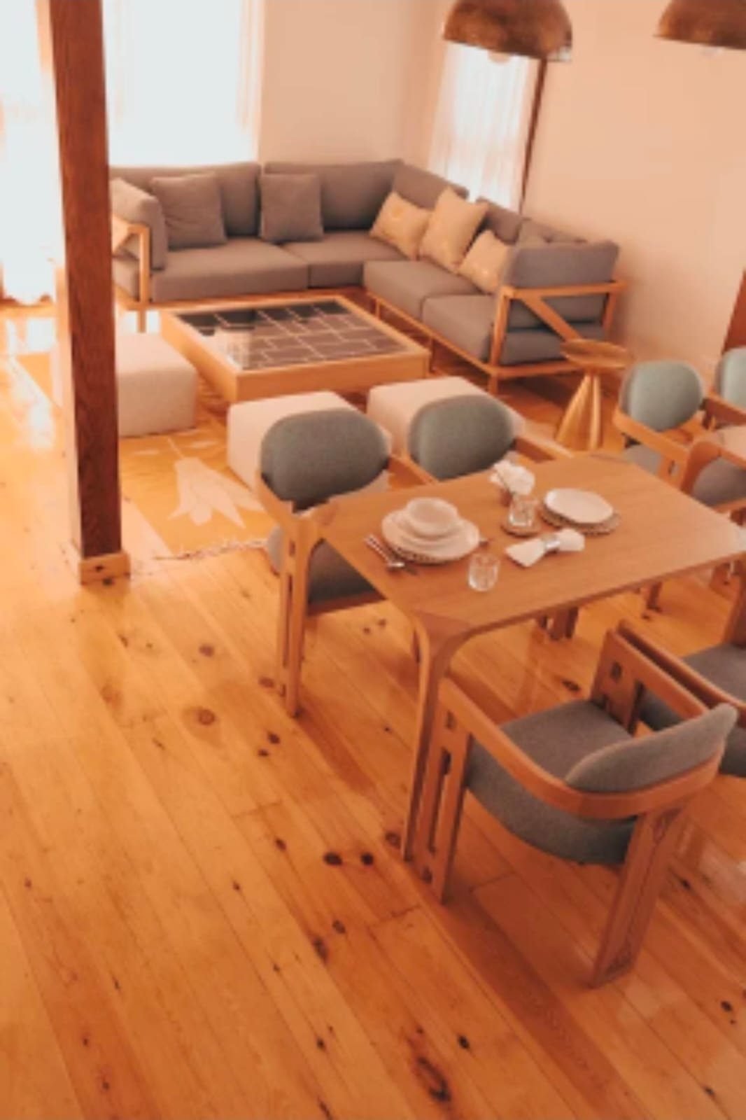 Rincón de comedor y salón de la Per-ba, con mesas de madera y luz natural