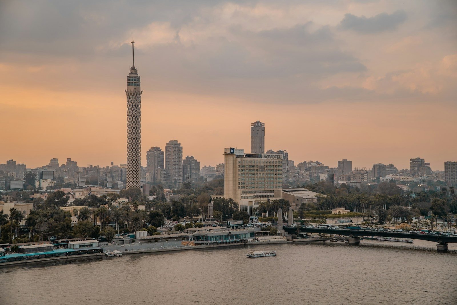Cairo at dusk seen from the Nile, with the Cairo Tower and the riverside buildings along the water.