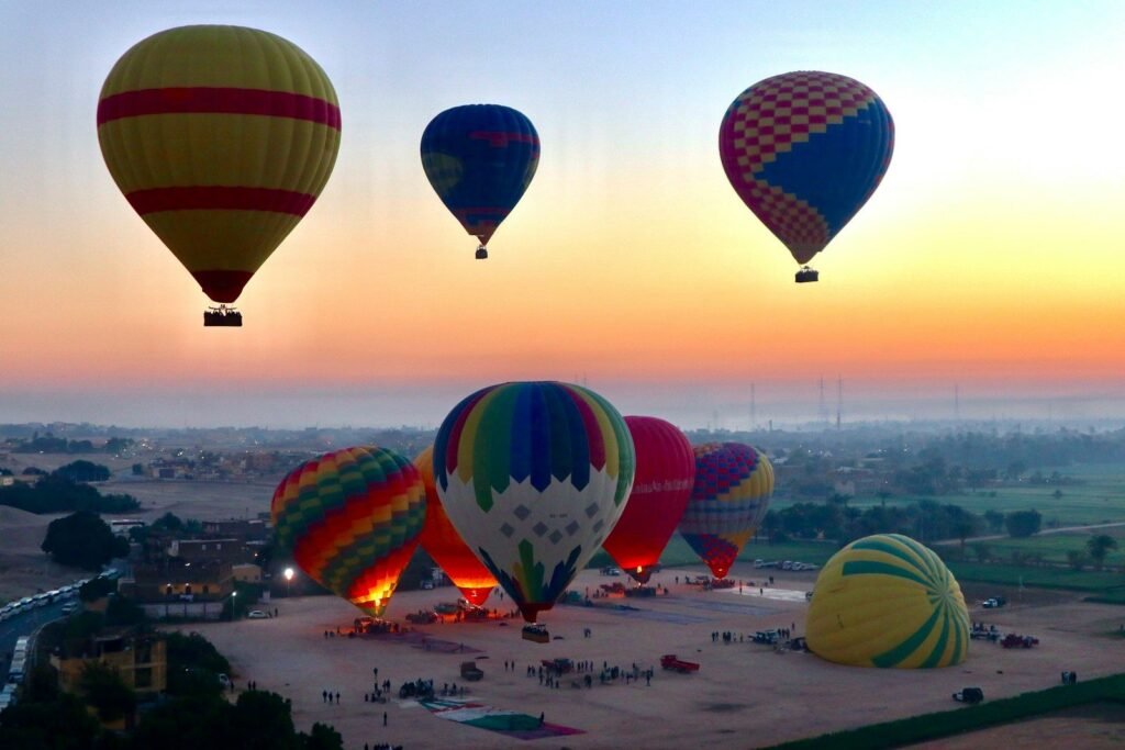 Hot air balloons inflating and lifting off at sunrise on the Luxor west bank