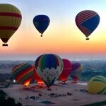 Hot air balloons inflating and lifting off at sunrise on the Luxor west bank
