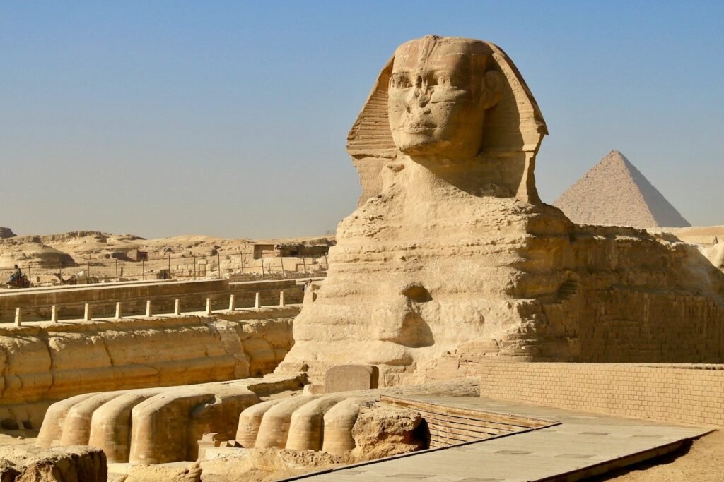 La Gran Esfinge de Giza con una de las pirámides detrás, bajo un cielo azul