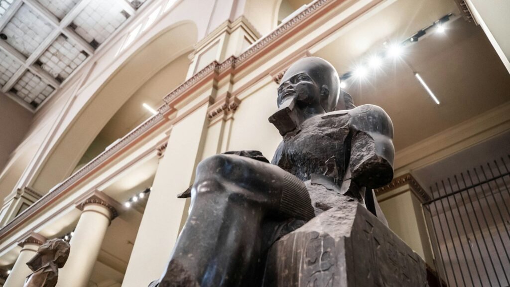 A seated dark granite statue in the central hall of the Egyptian Museum on Tahrir Square, Cairo