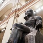 A seated dark granite statue in the central hall of the Egyptian Museum on Tahrir Square, Cairo