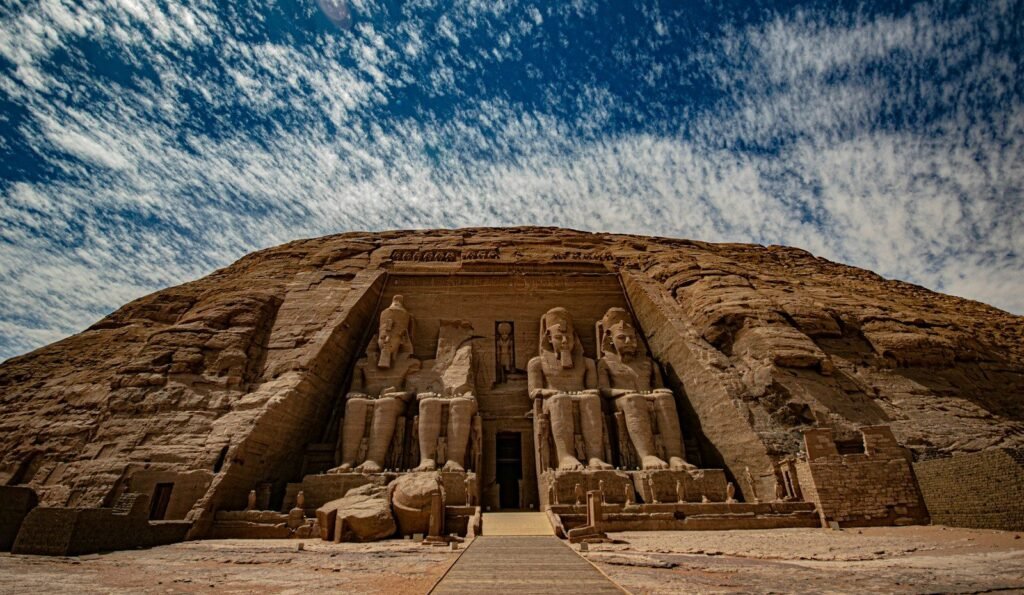 La fachada del Gran Templo de Abu Simbel con los cuatro colosos sentados de Ramsés II bajo un cielo de nubes