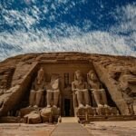 La fachada del Gran Templo de Abu Simbel con los cuatro colosos sentados de Ramsés II bajo un cielo de nubes