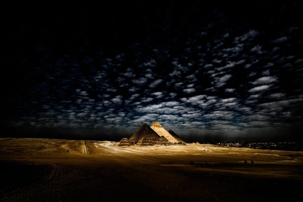 Las pirámides de Giza iluminadas de noche bajo un cielo de nubes
