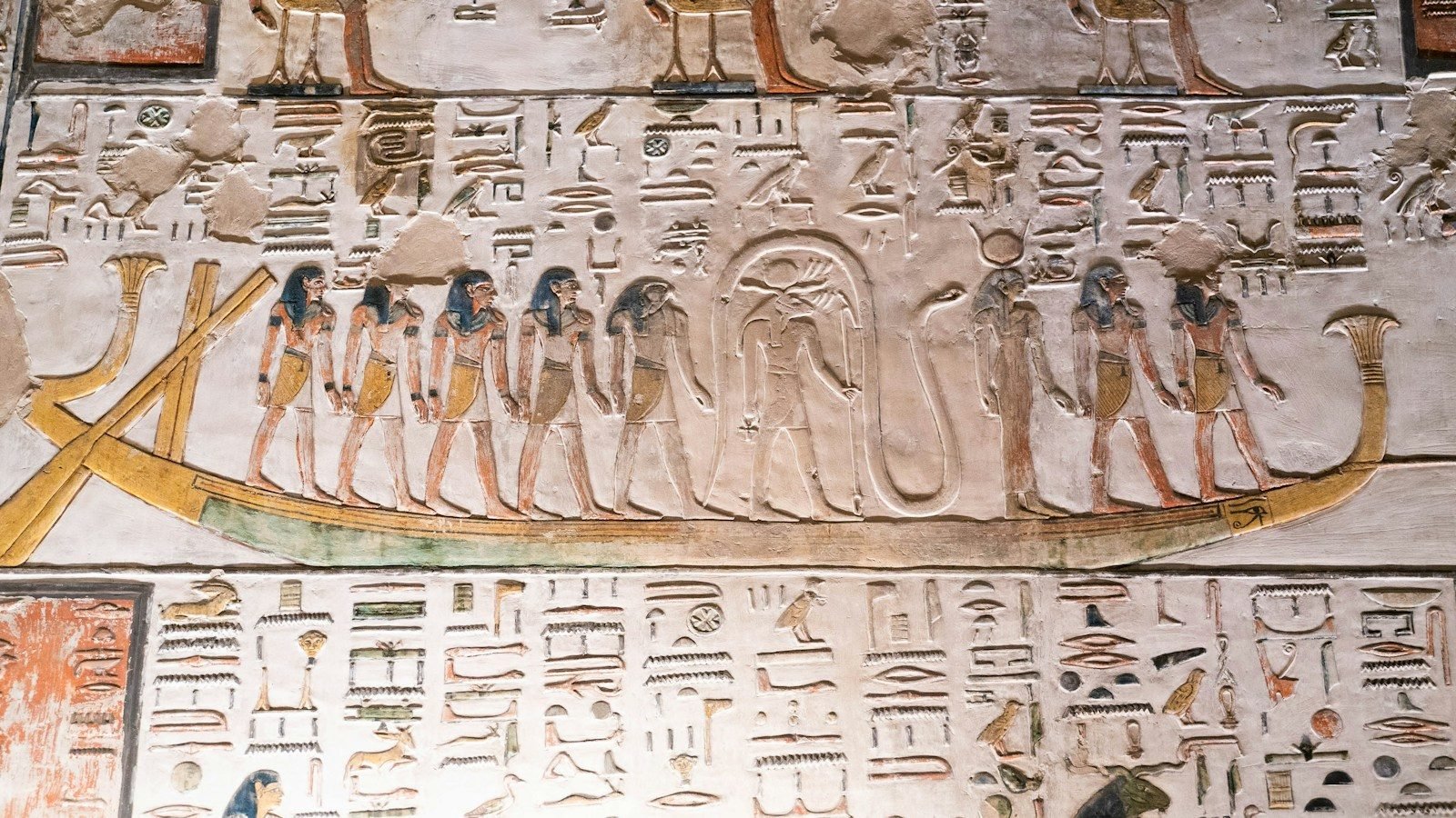 Relieve pintado de la barca solar con dioses y jeroglíficos en el muro de una tumba del antiguo Egipto.