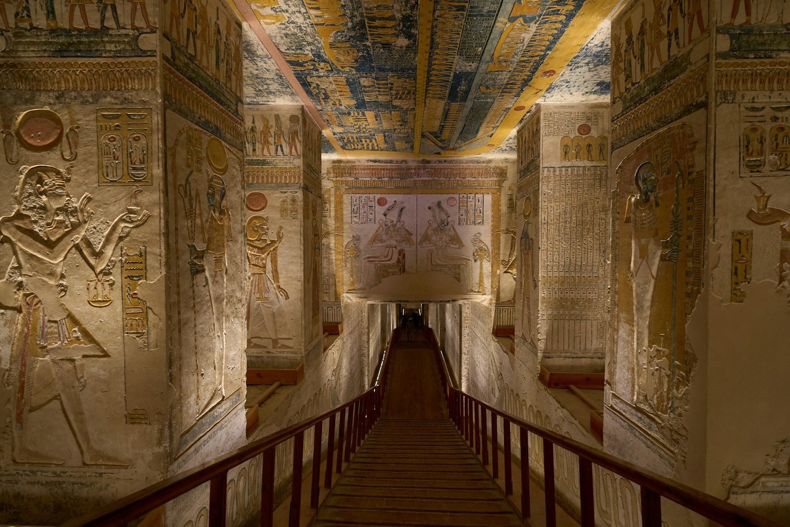 Pasillo pintado de una tumba del Valle de los Reyes, con relieves de colores y el techo decorado.