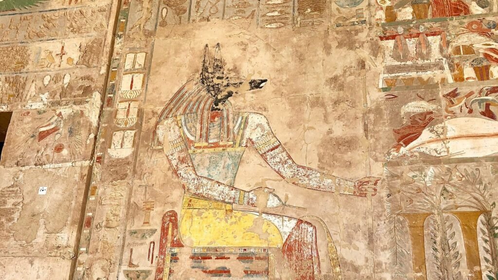 Relieve pintado de Anubis con cabeza de chacal negra, collar ancho y el anj en la mano, en la capilla de Anubis del templo de Hatshepsut en Luxor