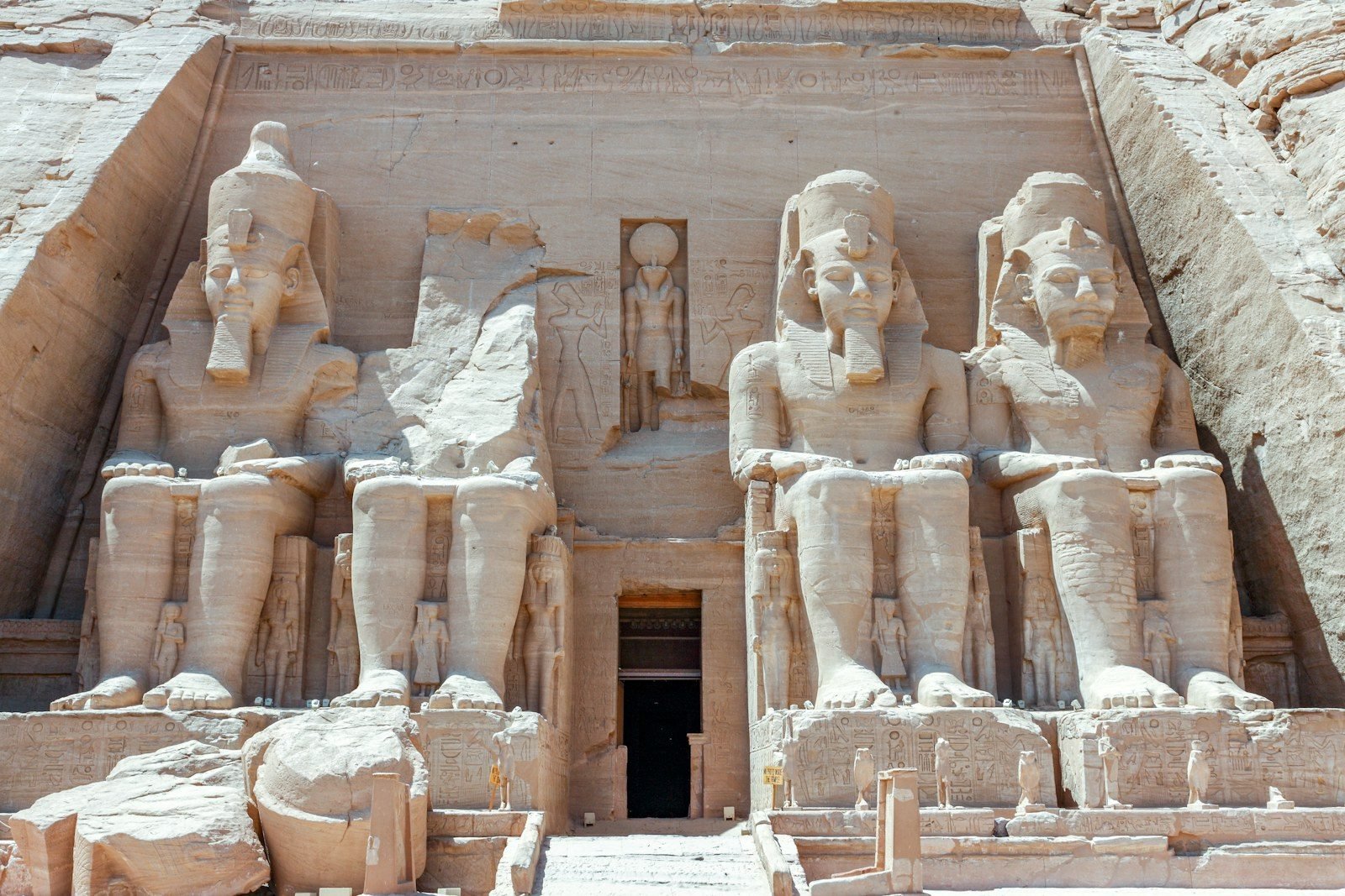 Frontal close view of the four seated colossi of Ramesses II on the facade of the Great Temple of Abu Simbel, with the entrance doorway in the middle.