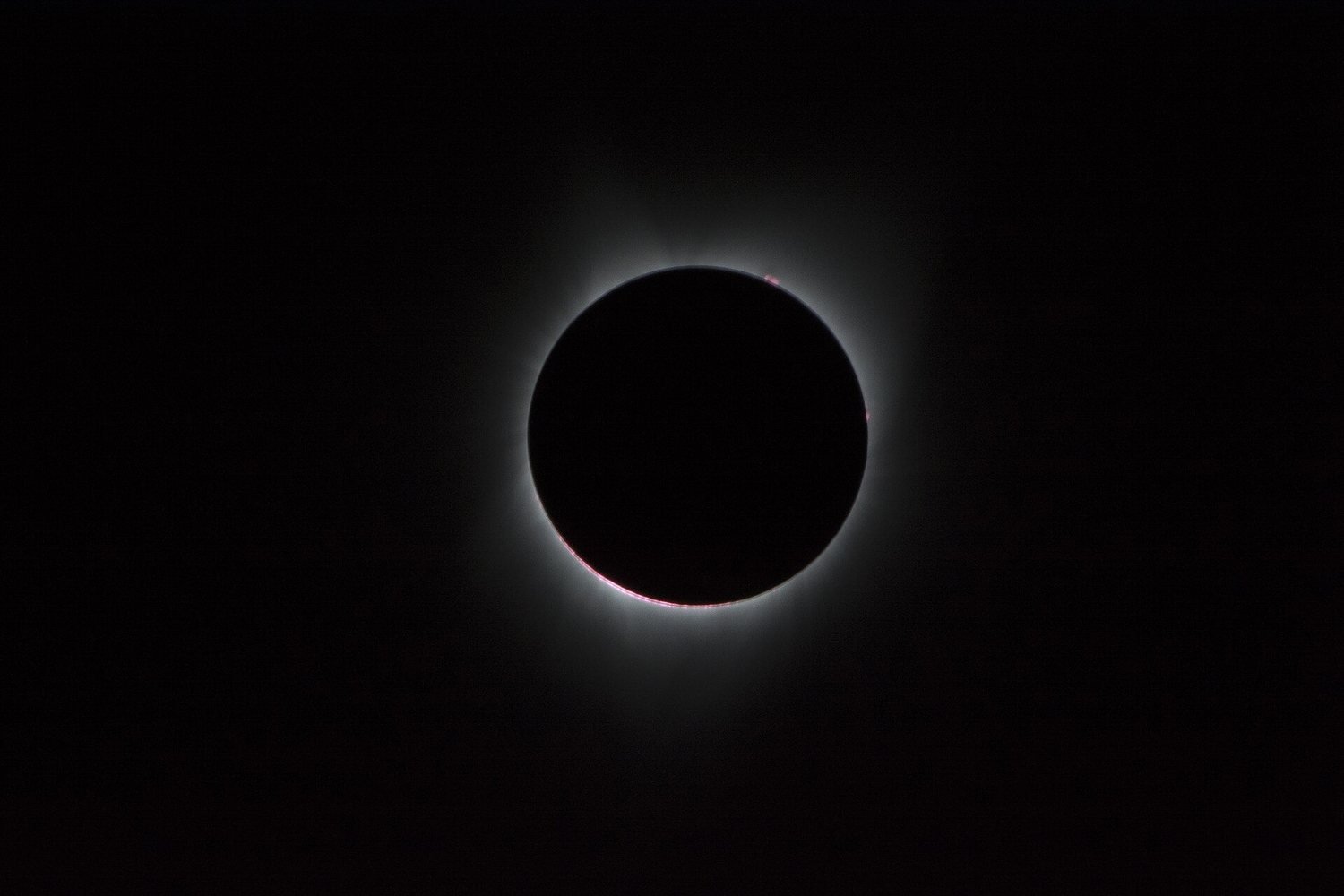 La corona solar rodea la Luna durante un eclipse solar total, con el cielo oscuro, en una fotografía de la NASA de 2017