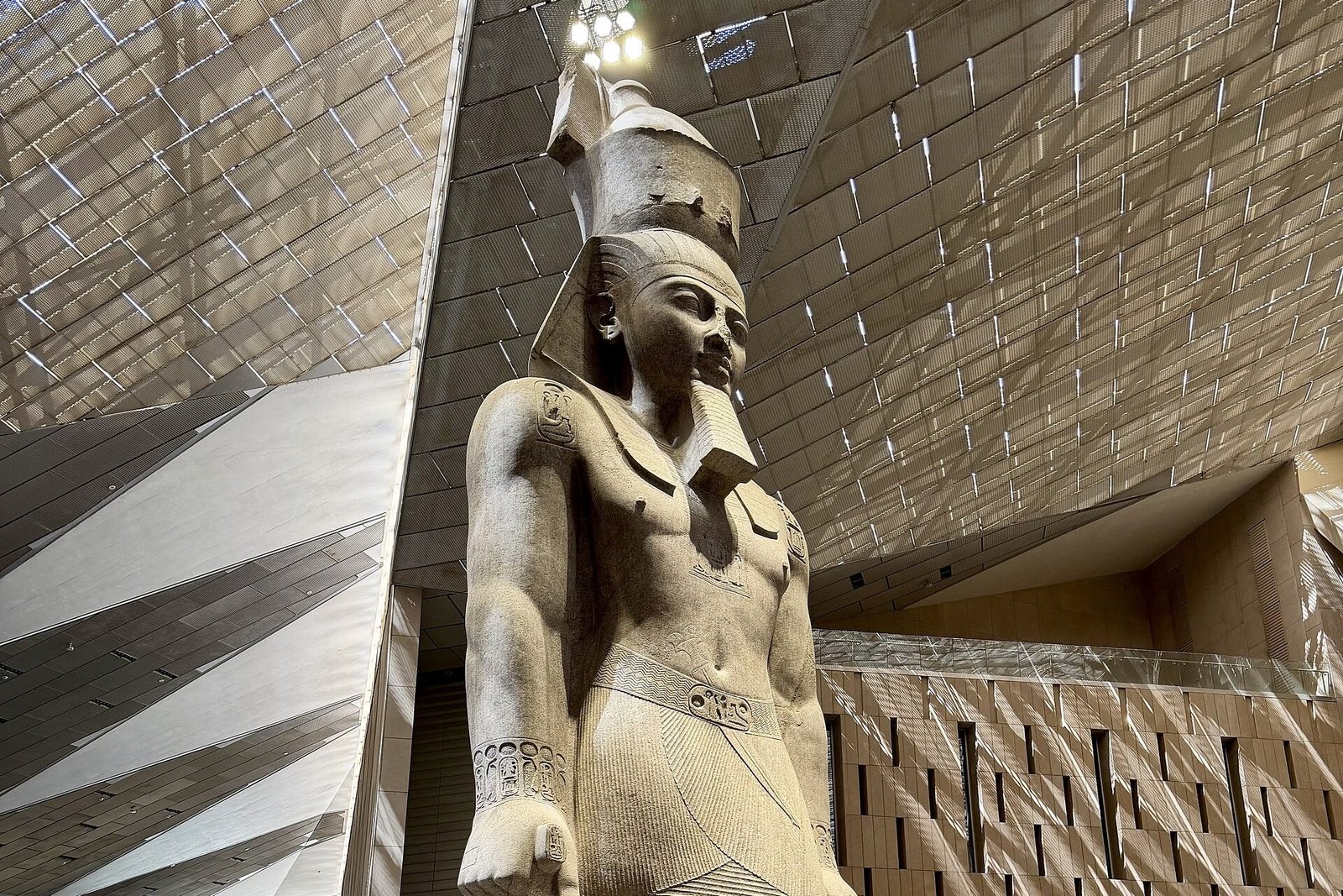 Estatua colosal de Ramsés II en el Gran Vestíbulo del Gran Museo Egipcio, bajo el techo triangular de cristal y piedra