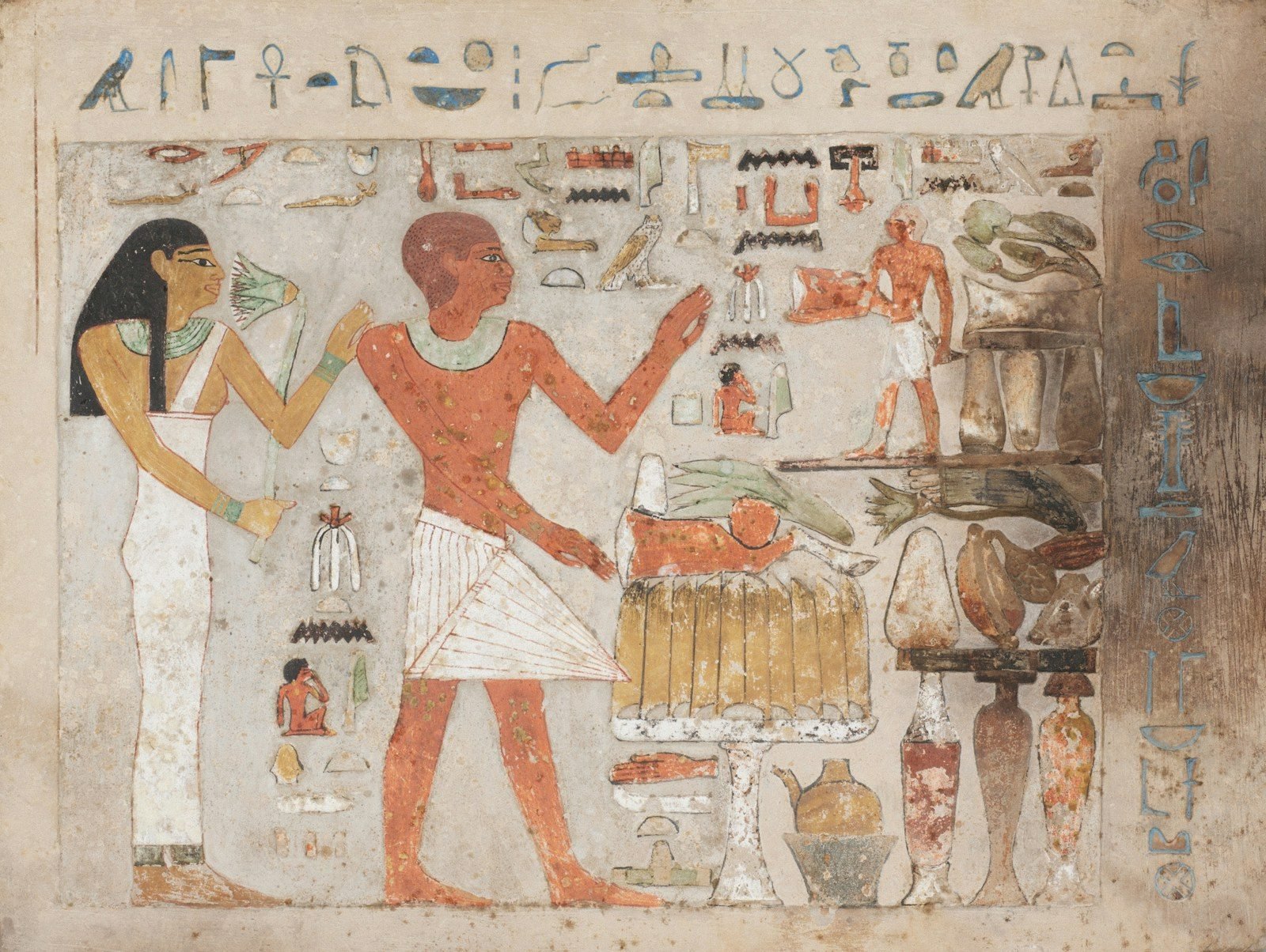 A painted limestone stela showing a man and a woman beside an offering table, with blue hieroglyphs.
