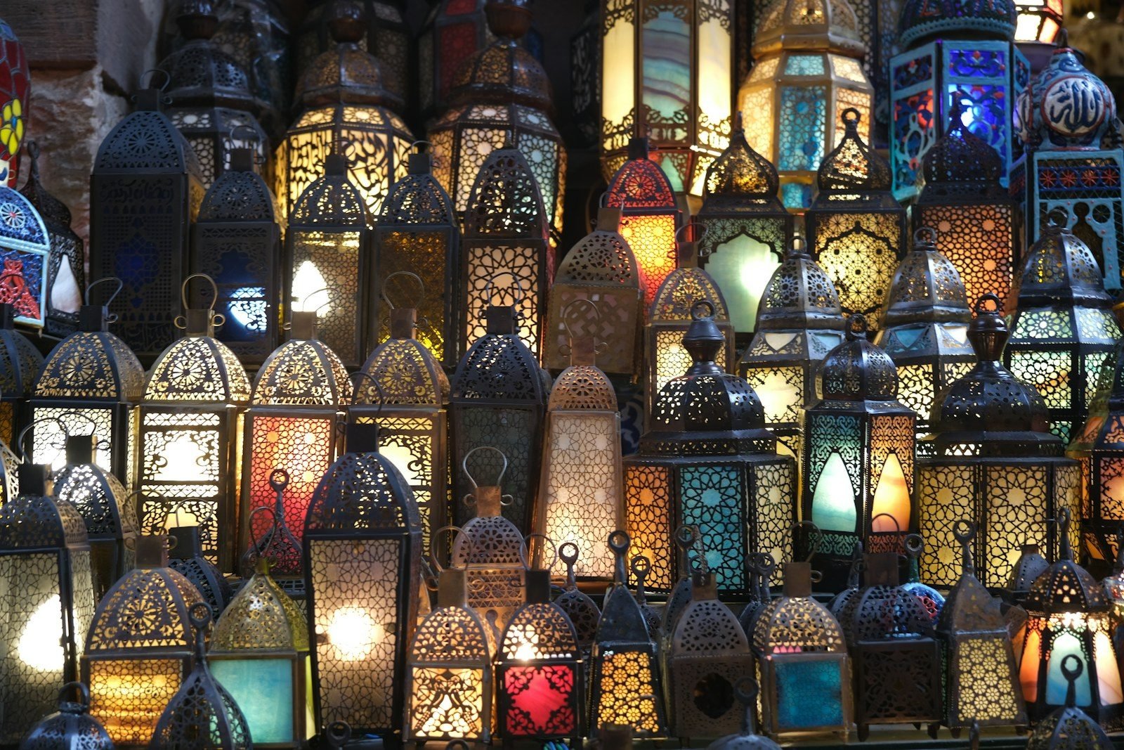 Linternas de metal calado con cristales de colores encendidas y apiladas en un puesto de mercado.