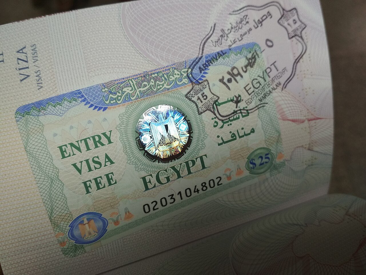 Página de pasaporte con la pegatina del visado de entrada a Egipto y un sello de llegada de aeropuerto superpuesto.
